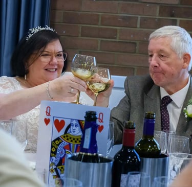 Smiling bride and groom toast with wine glasses at their wedding reception dinner table.