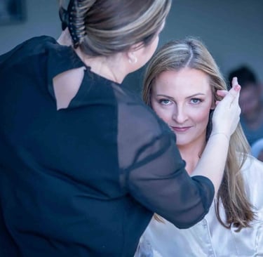 Professional bridal makeup artist applying finishing touches to a blonde bride on her wedding day.