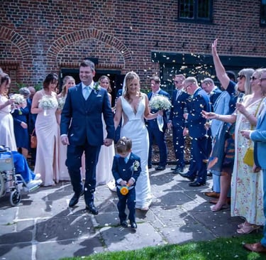 A happy bride and groom walking through a confetti toss at their outdoor wedding ceremony.