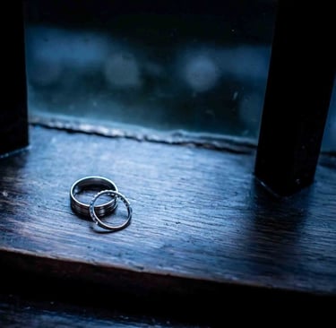 Wedding rings on a dark rustic wooden surface.