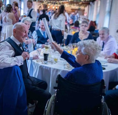 Elderly guests talking and laughing at a wedding reception seated at a round banquet table.