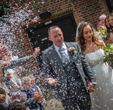 newly-wed running through confetti being thrown by guests