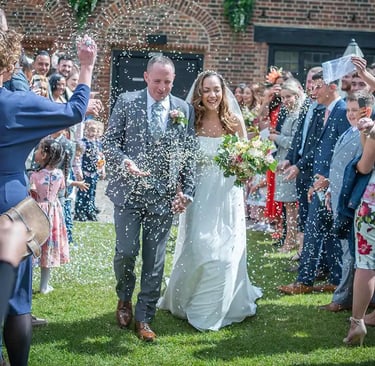 newly-wed running through confetti being thrown by guests