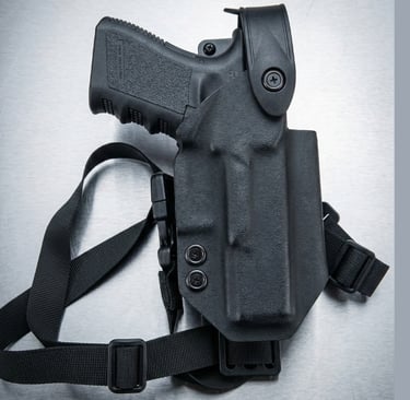 Black tactical Kydex holster with adjustable thigh strap holding a semi-automatic handgun.
