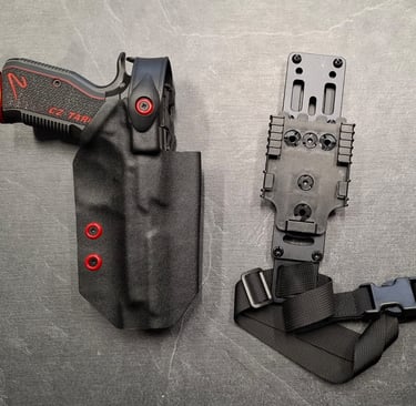 Custom black Kydex holster with red accents holding a CZ Shadow 2 pistol next to a tactical drop leg platform.