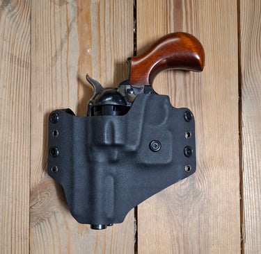 A classic revolver with a wooden grip secured in a black Kydex holster on a wooden background.
