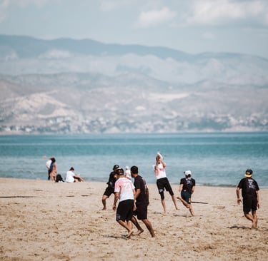 Fotografía de jugadores jugando ultimate frisbee en una playa de día