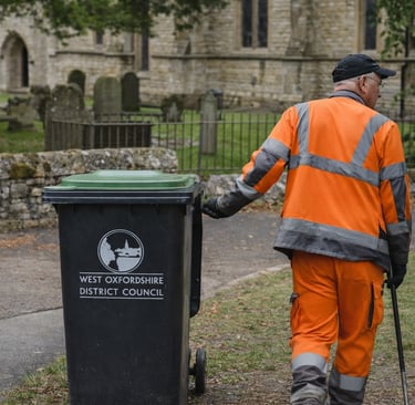 A council worker wearing PPE collecting a bin 