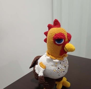Handmade crochet amigurumi chicken toy inspired by Stardew Valley standing on a dark wooden table.
