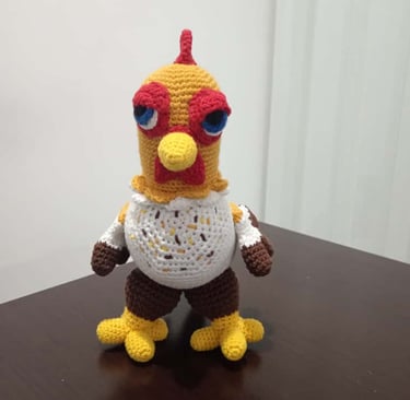 Handmade crochet amigurumi chicken plush toy standing on a dark wooden table.