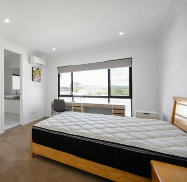 Bright bedroom with a mattress on a wooden frame and large window.