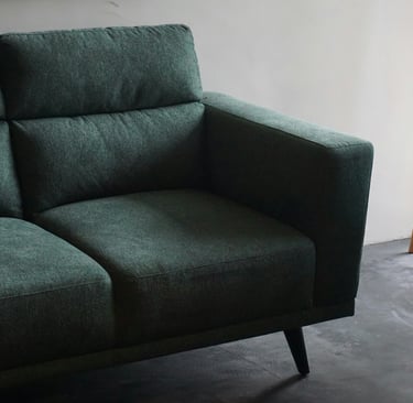 Green upholstered sofa in a modern room promoting fibre‑safe upholstery and mattress cleaning.