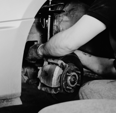 Professional mechanic performing brake pad replacement and suspension repair on a car.