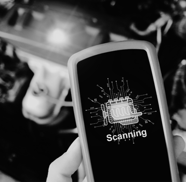 Handheld diagnostic tool scanning a car engine for automotive repair and troubleshooting.