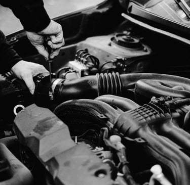 A mobile mechanic uses a screwdriver to perform car engine repair and maintenance.