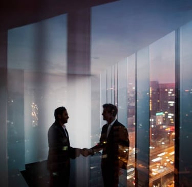 Business partners shaking hands in a high-rise office overlooking a city skyline at sunset.