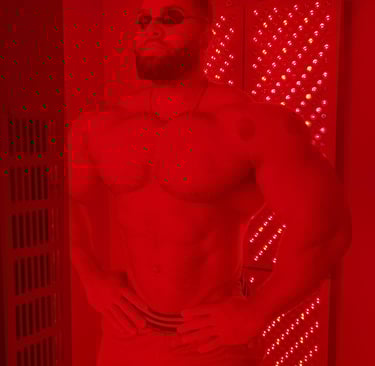 A muscular man uses a red light therapy panel for muscle recovery and skin health.
