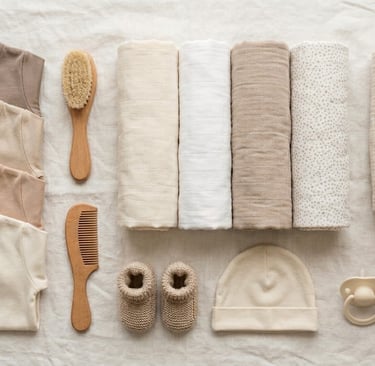 Bovenaanzicht van een newborn babyuitzet checklist met overslagrompertjes, opgerolde hydrofiele doek