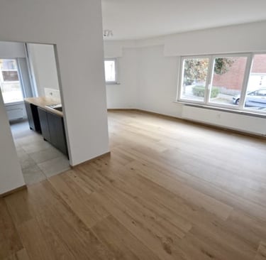 a room with a wooden floor and a kitchen