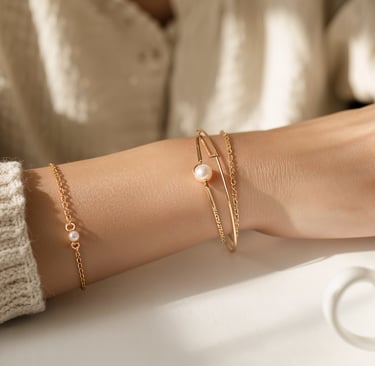 Elegant gold pearl bracelets and rings on a woman's arm beside a coffee cup.
