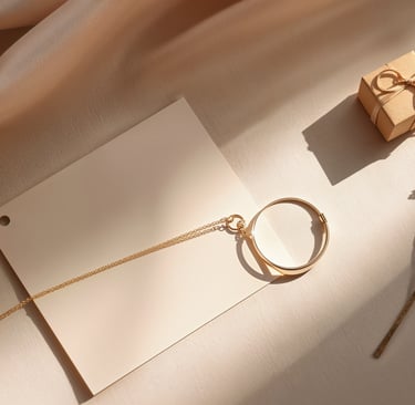 Elegant gold circular necklace on a cream stationery card with a small gift box and dried flowers.