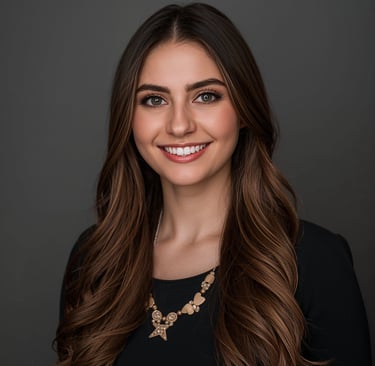 Professional headshot of a smiling woman with long brown wavy hair and a gold necklace.
