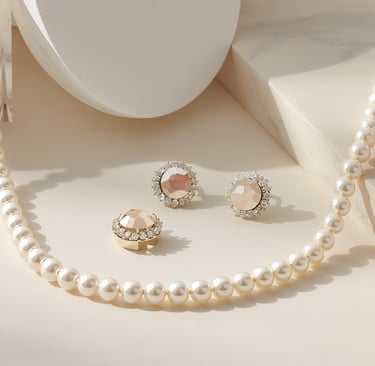 Elegant white pearl necklace and champagne crystal stud earrings displayed on a marble surface.