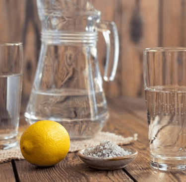 Caraffe d'eau avec deux verres et sur la table un citron et du sel de mer