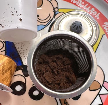 Ground coffee inside a reusable stainless steel mesh filter pod for coffee makers.