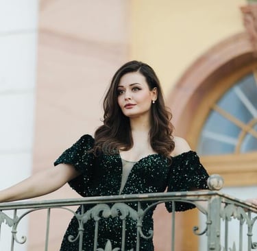 Mujer con vestido verde, posando con seguridad en un balcón clásico.
