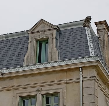 Architecture européenne historique avec un toit mansardé recouvert d'ardoises grises et une lucarne 