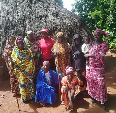 a group of people standing around a hut with a thatched roof