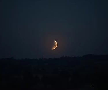 The crescent moon shining brightly in a darkened sky.