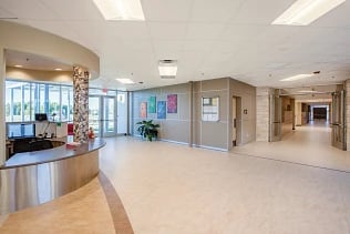 Modern school building lobby with a curved reception desk and brightly lit corridors.