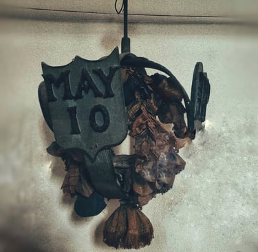 Rustic vintage wall hanging with metal May 10 shield and dried floral wreath decor.