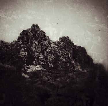 Vintage sepia-toned landscape of a rugged mountain peak with a textured, aged film overlay.