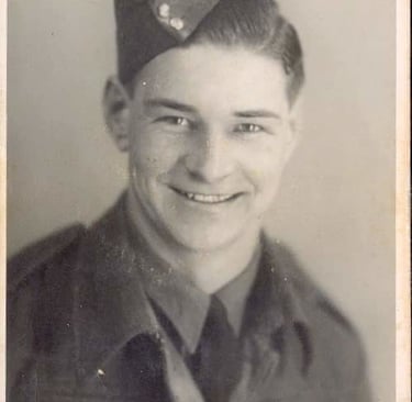 Vintage black and white portrait of a smiling young soldier in a military uniform and forage cap.