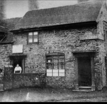 Vintage black and white photo of the historic Boat Inn brick pub with people standing outside.