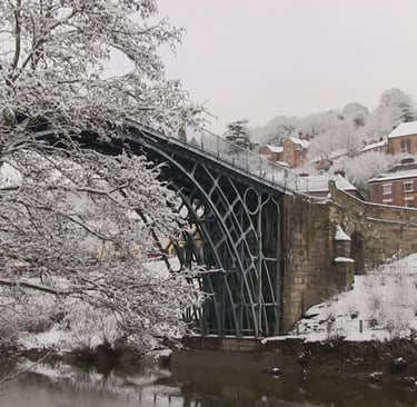 The Iron Bridge in Shropshire covered in winter snow with the Tontine Hotel and church in the background.