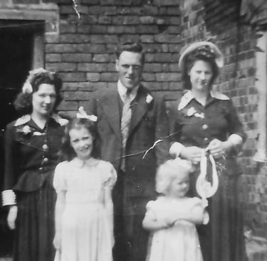 Vintage black and white portrait of a family of five posing in front of a brick wall.