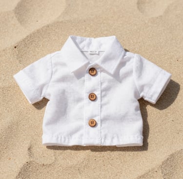 Camisa de perro y gato de lino blanco de manga corta con botones de madera, tendida sobre una playa de arena
