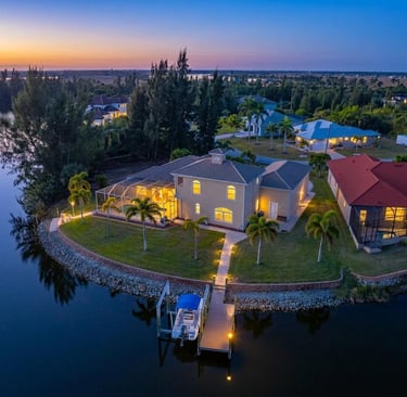 Aerial view of a luxury waterfront home with a private boat dock at sunset in Florida.