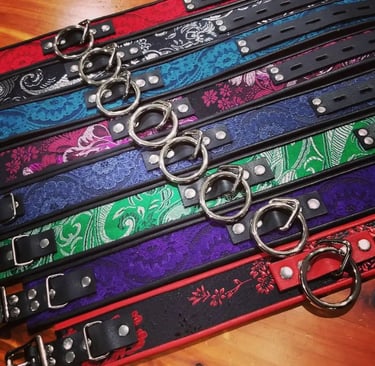 Handmade leather collars with metal O-rings in various floral patterns and colors.