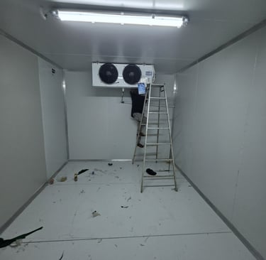A technician installs a commercial refrigeration unit inside a walk-in cold storage room.