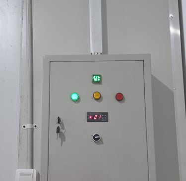 Industrial electrical control panel with digital temperature display and indicator lights.