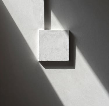 Una fotografía minimalista de un detalle arquitectónico en un estudio español con paredes de color blanco roto y sombras geométricas limpias. Estilo profesional y elegante.