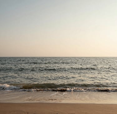 An evocative landscape photo of a tranquil beach at dawn. The sand is a Warm Sandy Taupe, and the gentle waves are a mix of Charcoal Olive and Muted Earth Brown reflections. The sky is a vast, serene Soft Creamy Off-White, reflecting a soulful and powerful connection to nature.