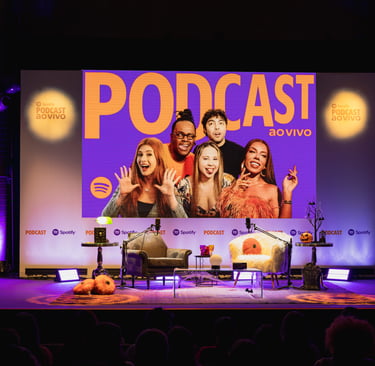 A live Spotify podcast stage with hosts on a large screen and chairs for a live recording event.
