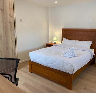 Habitación matrimonial amplia con cama cómoda, iluminación cálida y escritorio en hotel en Huayllay 