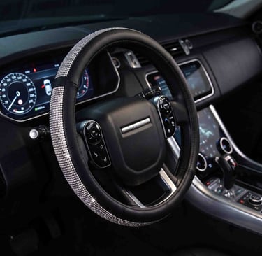 Black leather car steering wheel cover with sparkling rhinestone accents in a luxury vehicle interior.